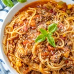Instant Pot Spaghetti on a white plate with loaf of bread on the side