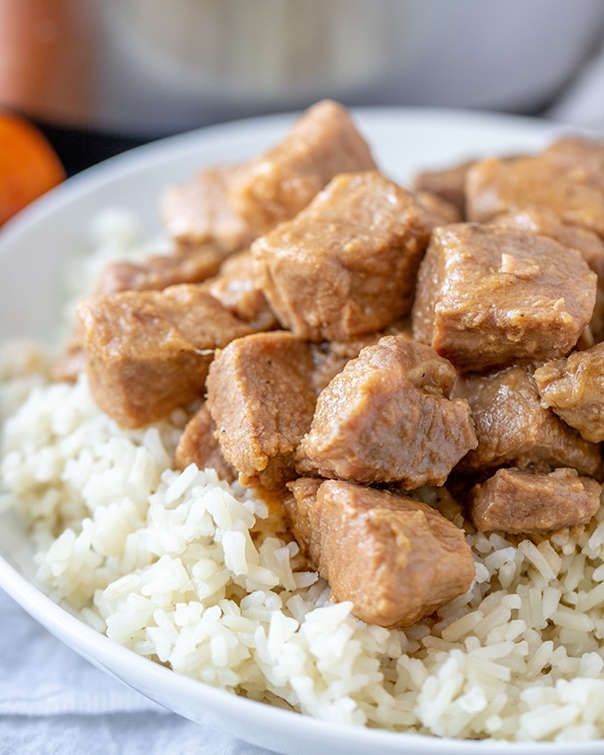 Pressure cooker pork adobo on steamed rice on a white plate