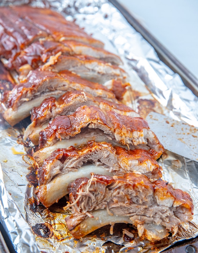 cut slab of Instant Pot BBQ pork ribs on a foil-lined baking sheet