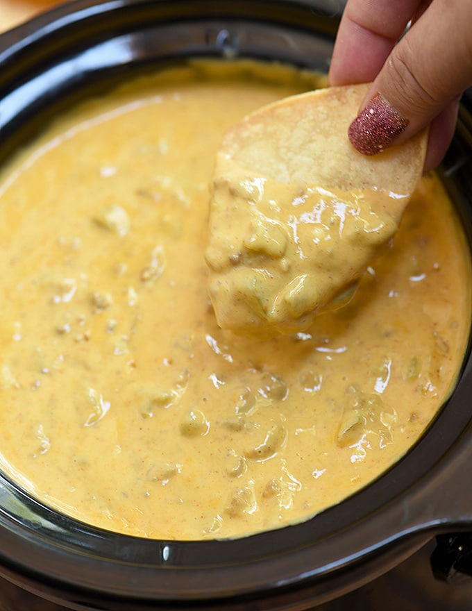 dipping corn chips in slow cooker queso dip