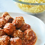 Instant Pot Turkey Meatballs with marinara sauce on a white plate with shredded Parmesan cheese on the side