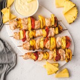 Hawaiian chicken kabobs with pineapples and bell peppers on a white platter
