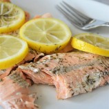 pressure cooker lemon dill salmon with sliced lemons on a white plate