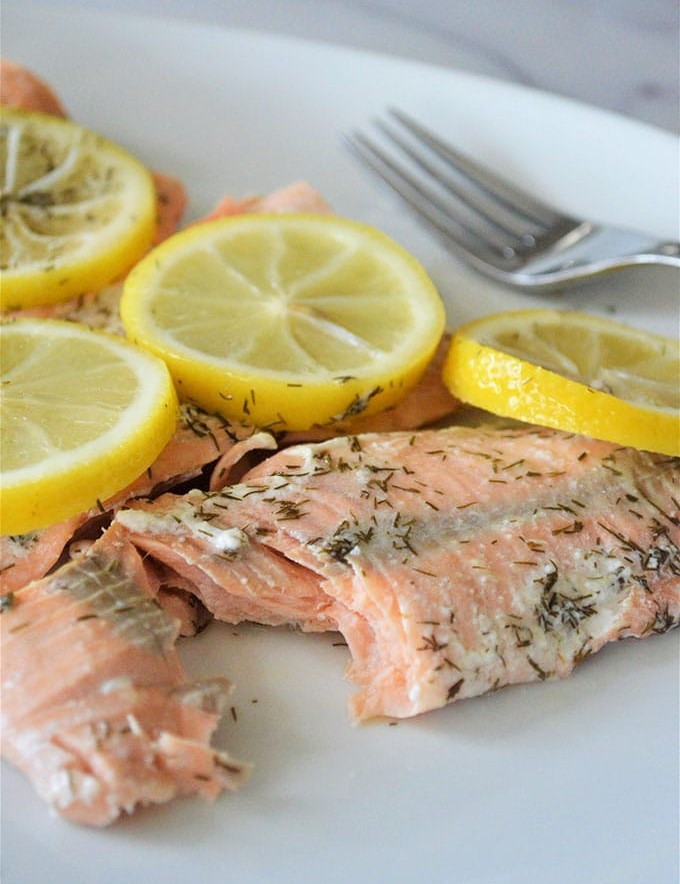 pressure cooker lemon dill salmon with sliced lemons on a white plate