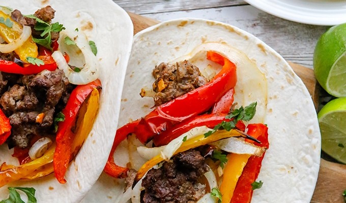 steak fajitas with onions and bell peppers on flour tortillas