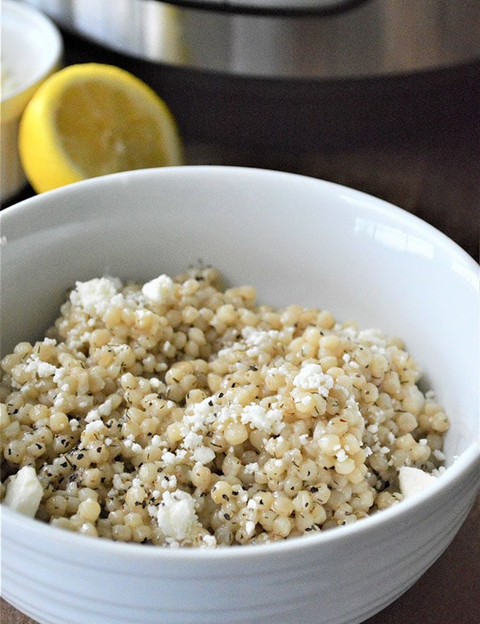 Instant Pot Israeli Couscous topped with feta cheese in a white bowl