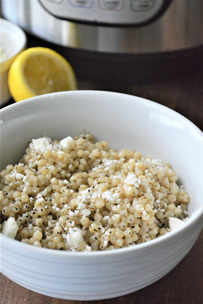 Instant Pot Israeli Couscous topped with feta cheese in a white bowl