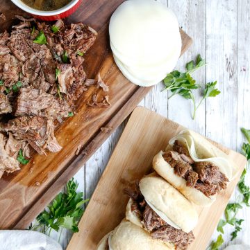 Instant Pot French Dip Sandwiches on a wooden board with pressure cooker roast beef in another wood board