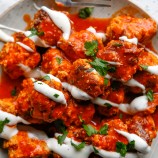 pressure cooker chicken meatballs with buffalo sauce, ranch dressing, and chopped parsley on a white plate