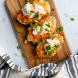 Air Fryer Twice-Baked Potatoes topped with sour cream and green onions on a board