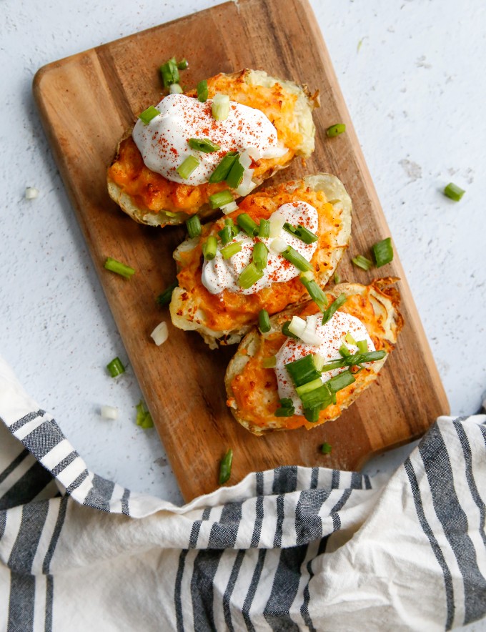 Air Fryer Twice-Baked Potatoes topped with sour cream and green onions on a board