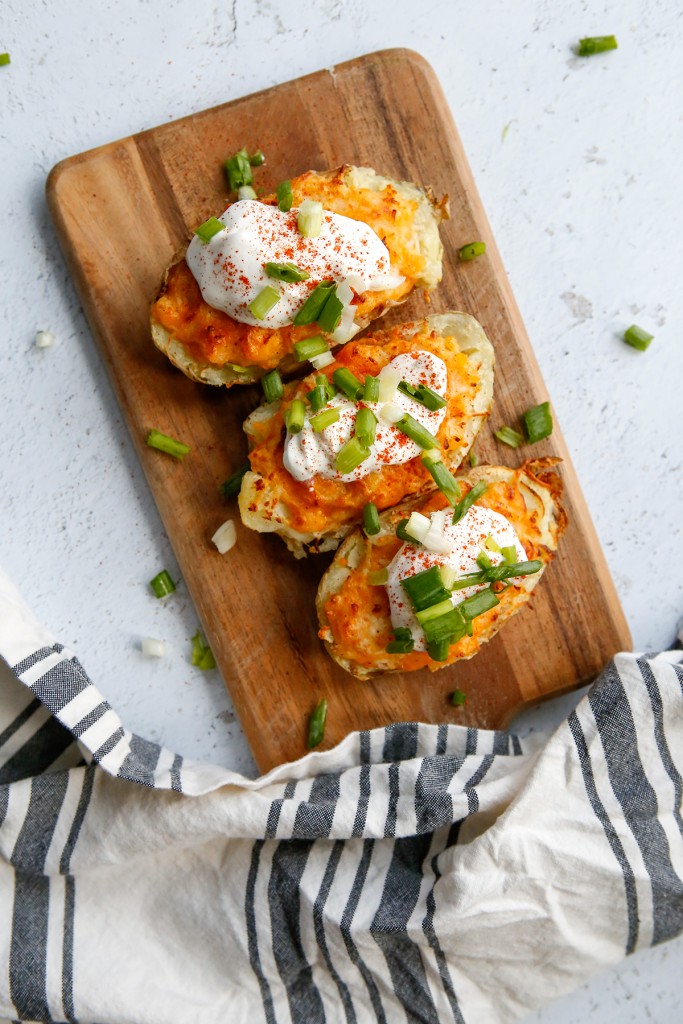Air Fryer Twice-Baked Potatoes topped with sour cream and green onions on a board